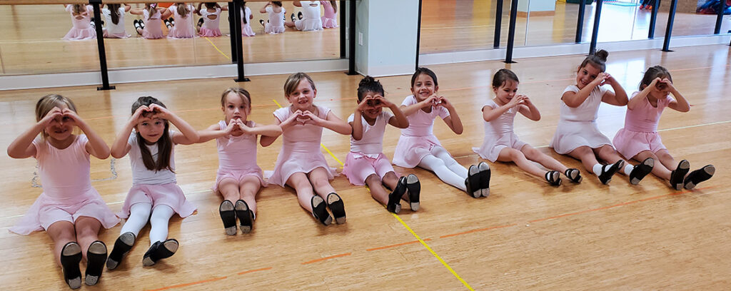 Small children in ballet class, wearing traditional pink ballet costumes