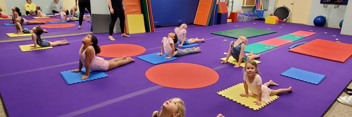 Elementary-age schoolchildren stretching in a gym for tumbling class