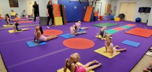 Elementary-age schoolchildren stretching in a gym for tumbling class