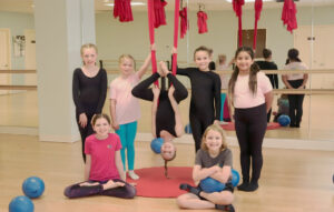 Kids at an aerial acrobatics group activity, with red hammocks/silks.